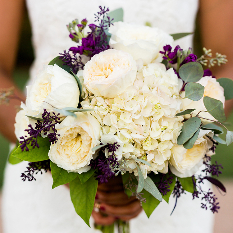 OKCFM_Tiles-42 Elegant wedding floral arrangement of white peonies, hydrangeas, purple stock flowers, and silver dollar eucalyptus greenery held by a bride.